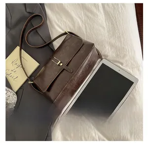 Détail d'un sac bandoulière vintage en cuir marron avec boucle dorée élégante