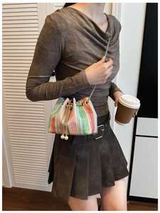Detailed shot of multi-color woven bucket bag featuring elegant pearl pendants on drawstring