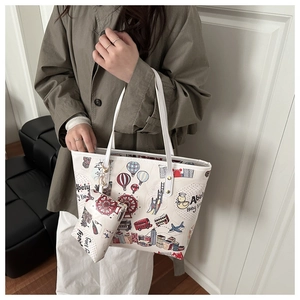 Detail of white cartoon tote bag featuring city illustrations and a matching small pouch