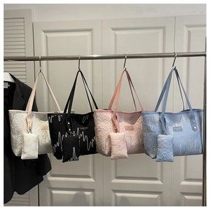 Close-up of four quilted tote bags in white, black, pink, and blue with matching pouches