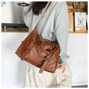 Detail of a brown vintage leather tote bag with sturdy metal hardware and strap