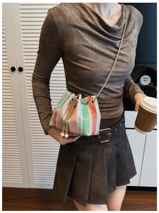 Detail of colorful woven bucket bag with gold chain strap and pearl drawstring charms