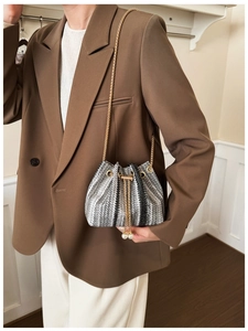 Detail of knit bucket bag with gold chain strap and pearl drawstring tassels