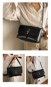 Close-up of black crossbody bag featuring fine leather texture and golden metal buckle