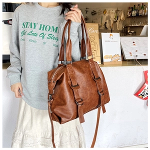Brown PU leather tote bag with adjustable strap shown in a trendy cafe setting
