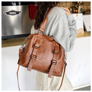 Detailed view of caramel brown tote bag with metal buckles and versatile straps in a cafe