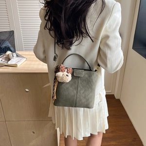 Retro grey-green suede bucket bag with bear charm and scarf shown in use