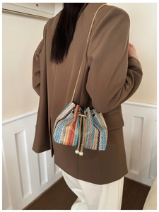 Detail of colorful woven bucket bag with pearl drawstring charms and gold chain strap