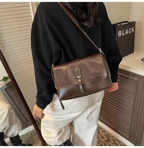 Gros plan du sac bandoulière marron vintage avec texture craquelée et boucle dorée