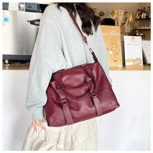 Scene showing large burgundy pebble leather tote bag with wide shoulder strap used by model
