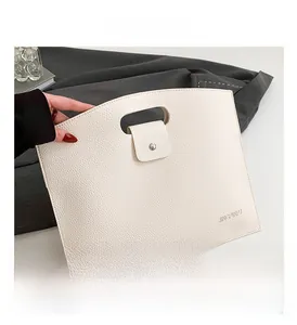 Detail of off-white lychee texture faux leather handbag with cutout handle and metal buckle