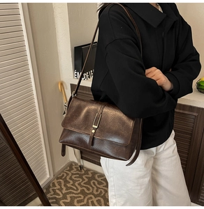 Close-up of deep brown oil-wax leather texture with gold metal hardware on crossbody bag