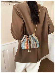 Rainbow woven bucket bag with pearl charms and gold chain strap shown on a model