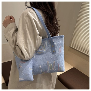Detailansicht einer hellblauen Shopper-Tasche mit Textur, getragen von einem Modell