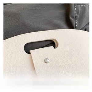 Close-up of cream leather handbag showing litchi texture and oval handle detail