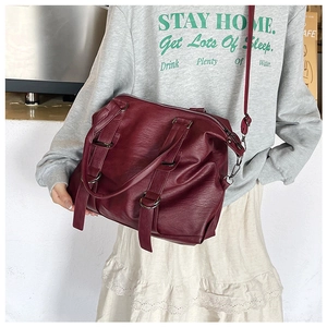Detail of dark red tote bag in textured faux leather with dual handles and silver hardware