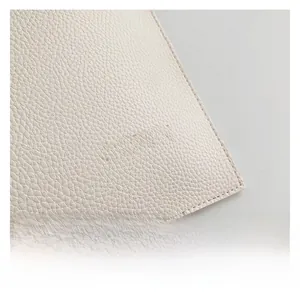 Close-up of white lychee pattern leather with embossed logo and neat stitching details