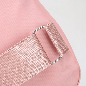 Macro detail of pink nylon sling bag showing durable shoulder strap and metal buckle