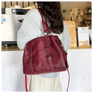 Rear view of a model carrying a vintage burgundy PU leather tote bag in a cozy cafe