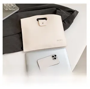 Detail showing creamy white litchi grain leather laptop bag with buckle strap closure