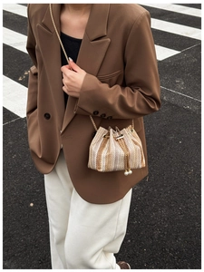 Close-up of a striped woven bucket bag with gold chain strap and pearl drawstring detail