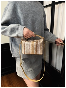 Detail of striped woven shoulder bag with yellow leather straps and metal buckle closure