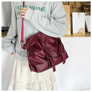 Close-up of wine red PU leather tote bag featuring a vibrant pink woven shoulder strap