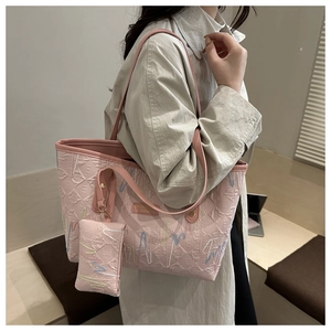 Detailansicht der rosa gesteppten Tragetasche mit Stickerei auf hellem Trenchcoat