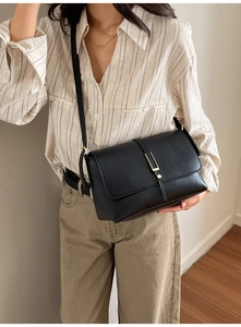 Détail d'un sac à bandoulière vintage noir avec boucle en métal doré et texture en cuir PU