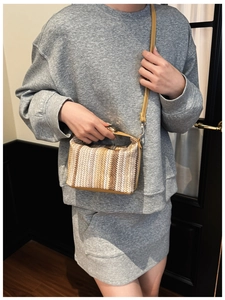 Détail du sac bandoulière tissé à rayures avec poignée en cuir jaune et fermoir doré