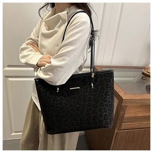 Detail of trendy leopard print tote bag with golden metal trim on female model