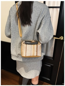 Rear view of a model wearing a striped straw crossbody bag with yellow leather details