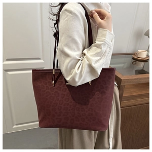 Detail of burgundy leopard print tote bag with gold metal buckles and slim shoulder straps