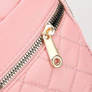Detail of pink quilted crossbody bag with luxury gold zipper and diamond stitch pattern