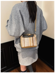 Détail d'un sac boîte tissé à rayures avec boucle dorée et fine bandoulière