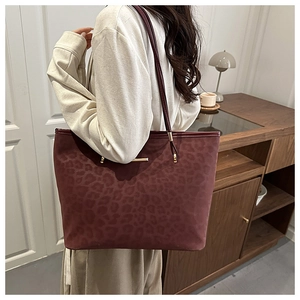 Detail of burgundy leopard print tote bag with gold hardware and slim shoulder strap