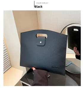 Détail d'un sac à main en cuir grainé noir avec bouton pression argenté et poignée