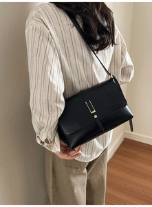 Gros plan d'un sac bandoulière en cuir noir avec boucle dorée porté par un mannequin