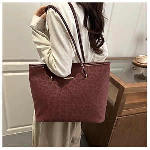 Close-up of leopard print burgundy tote bag featuring elegant golden metal hardware