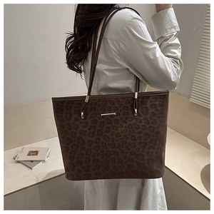 Detailed side view of the brown leopard print tote bag shown on a female model