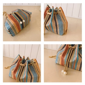 Detail of colorful woven bucket bag featuring pearl charms and a gold chain strap