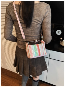 Close-up of woven crossbody bag with colorful stripes and pink leather strap