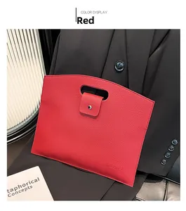 Détail d'un sac à main rouge en cuir grainé avec poignée découpée et bouton pression métal