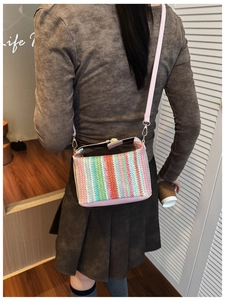 Close-up of vibrant multi-color striped knitted crossbody bag with pink leather strap