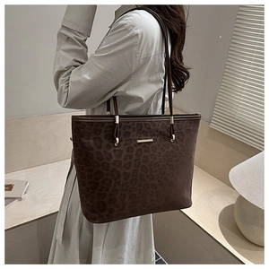 Detail of leopard print tote bag with matte texture and gold-tone brand hardware