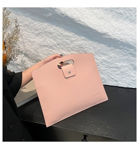 Detail of pink pebbled leather handbag featuring cutout handle and magnetic clasp closure