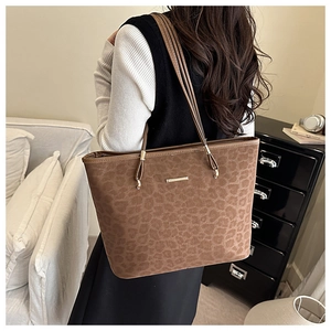 Close-up of leopard print suede tote bag with elegant gold metal tag and slender straps