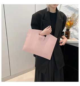 Detail of light pink pebble leather tote bag with cut-out handle and snap button closure