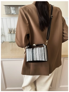 Détail de la texture tissée à rayures et fermoir doré d'un petit sac carré bandoulière