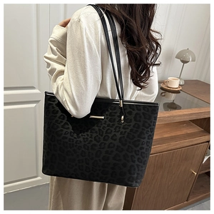 Lifestyle shot of large black leopard print tote bag with gold metal trim and leather straps